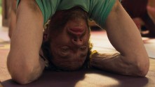 close-up of the face and arms of a man in an inverted yoga pose